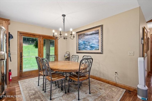 dining space with a chandelier, wood finished floors, and baseboards