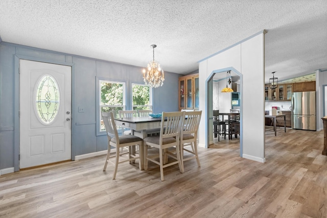 dining room featuring a chandelier, light hardwood / wood-style floors, and a textured ceiling