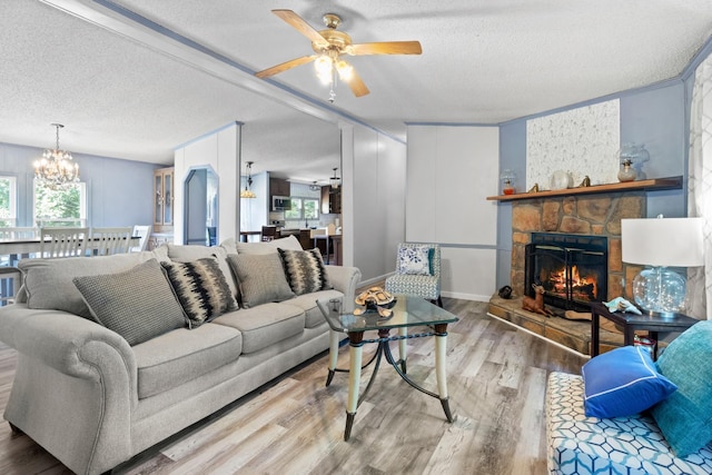 living room featuring light hardwood / wood-style flooring, a textured ceiling, a fireplace, and a healthy amount of sunlight