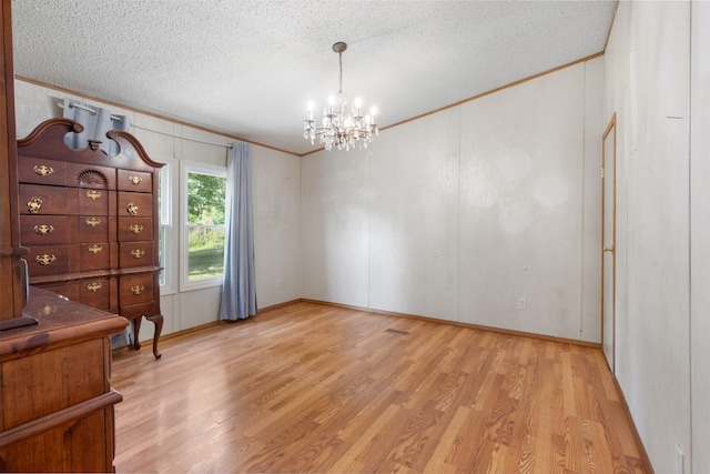 interior space featuring crown molding, an inviting chandelier, a textured ceiling, and light wood-type flooring