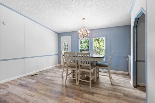 dining space with an inviting chandelier, a textured ceiling, and light wood-type flooring