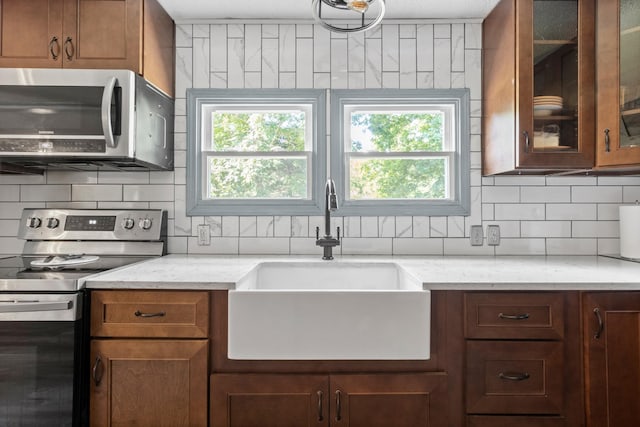 kitchen with sink, backsplash, light stone countertops, and appliances with stainless steel finishes