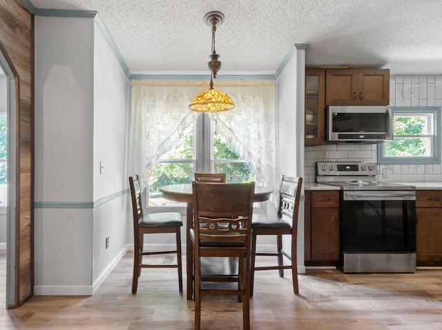 dining room featuring ornamental molding, a textured ceiling, and light hardwood / wood-style flooring