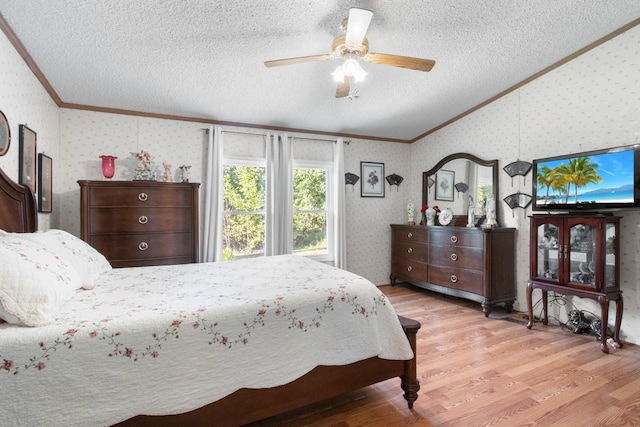 bedroom with lofted ceiling, a textured ceiling, ornamental molding, ceiling fan, and light hardwood / wood-style floors