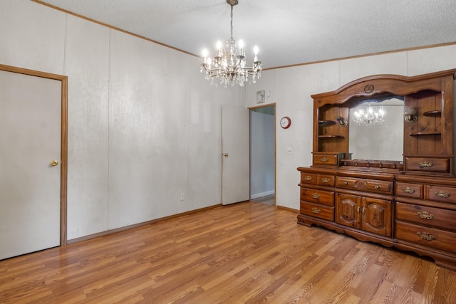 unfurnished bedroom featuring ornamental molding, a chandelier, a textured ceiling, and light wood-type flooring