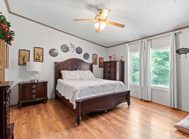 bedroom with vaulted ceiling, ceiling fan, light hardwood / wood-style floors, crown molding, and a textured ceiling