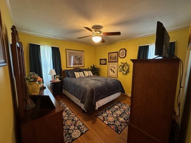 bedroom with ceiling fan, crown molding, and hardwood / wood-style flooring