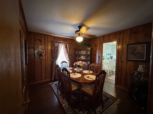 dining area featuring ceiling fan, wood walls, and hardwood / wood-style floors