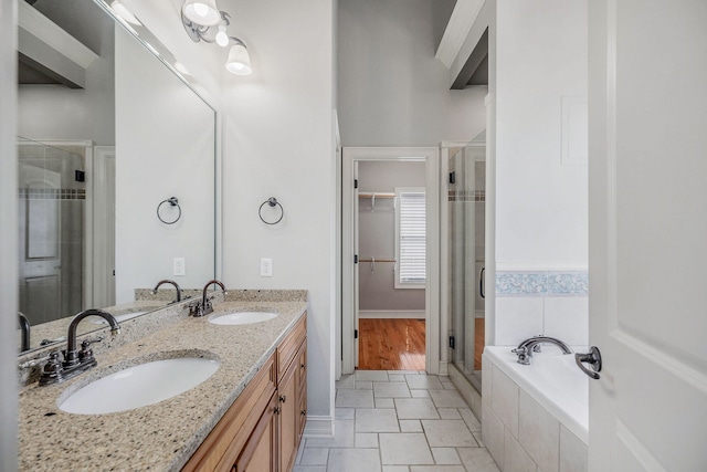 bathroom featuring plus walk in shower, double vanity, and wood-type flooring