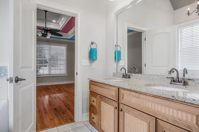 bathroom featuring tile patterned floors, ornamental molding, a tray ceiling, vanity, and ceiling fan