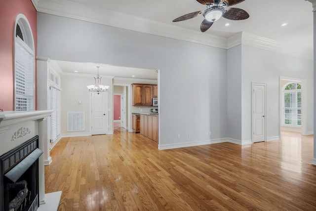 unfurnished living room with crown molding, ceiling fan with notable chandelier, and light hardwood / wood-style floors