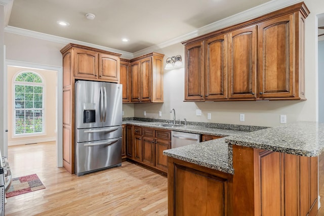 kitchen with sink, crown molding, appliances with stainless steel finishes, kitchen peninsula, and dark stone counters