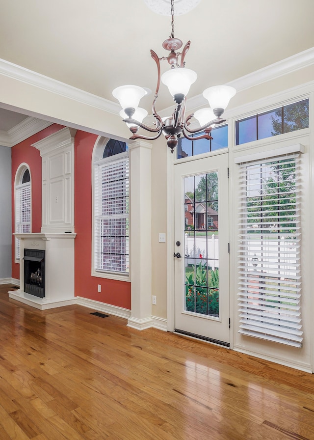 doorway featuring light hardwood / wood-style flooring, crown molding, and an inviting chandelier