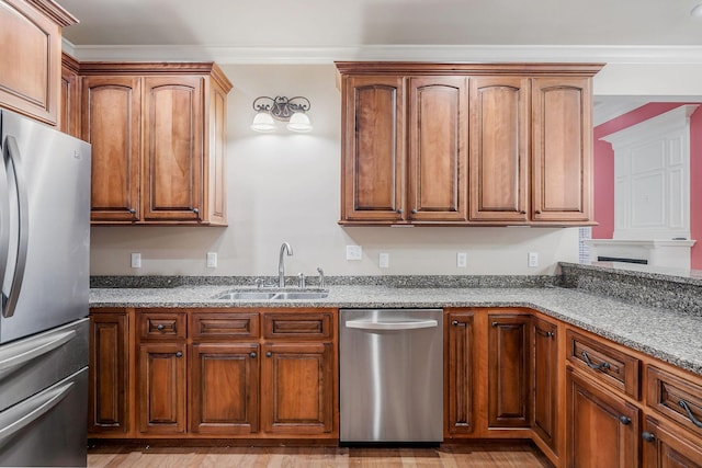 kitchen featuring ornamental molding, stainless steel appliances, light stone countertops, and sink