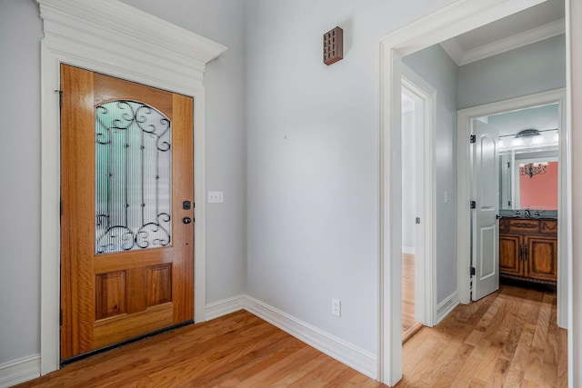 foyer entrance with ornamental molding, sink, and light wood-type flooring