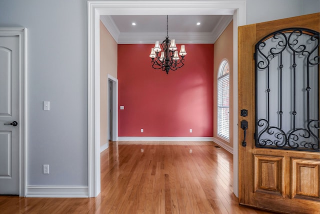 entrance foyer featuring crown molding, an inviting chandelier, and wood-type flooring