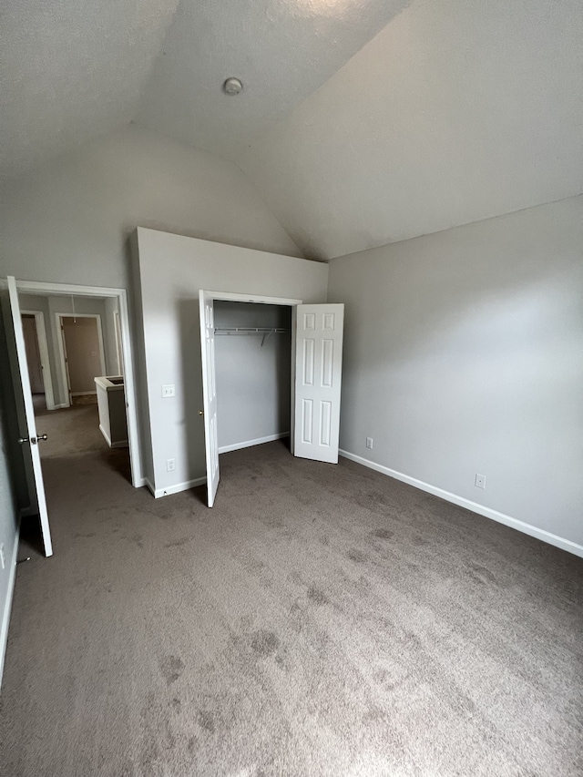 unfurnished bedroom featuring dark carpet, vaulted ceiling, and a closet