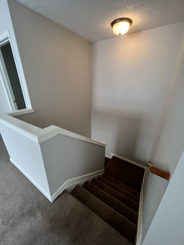 stairs with carpet and a textured ceiling