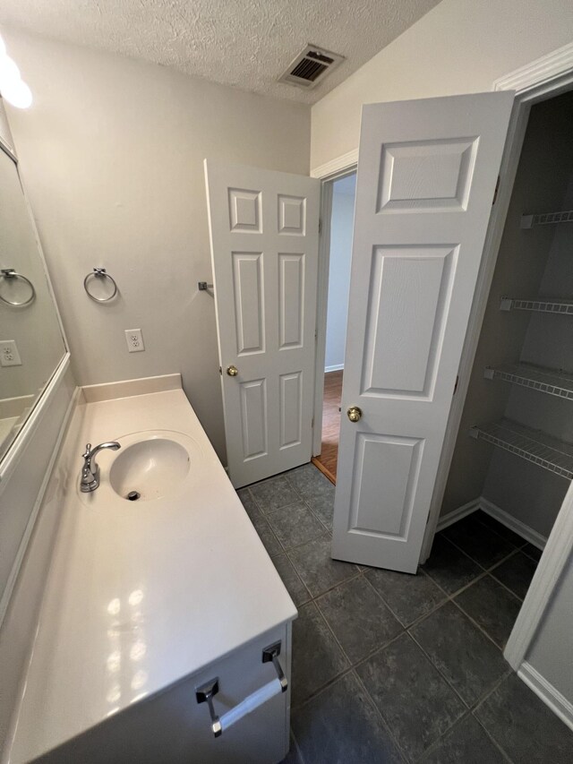 bathroom featuring vanity, a textured ceiling, and tile patterned flooring