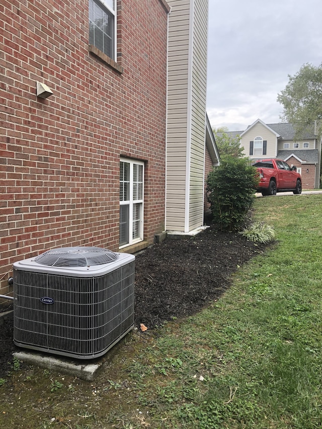 view of side of home with central air condition unit and a yard