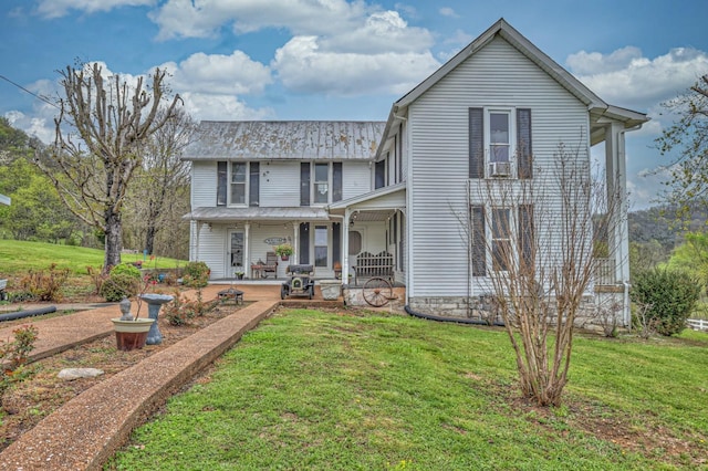 rear view of house featuring a porch and a lawn