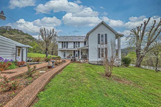 back of house featuring covered porch, a lawn, and fence