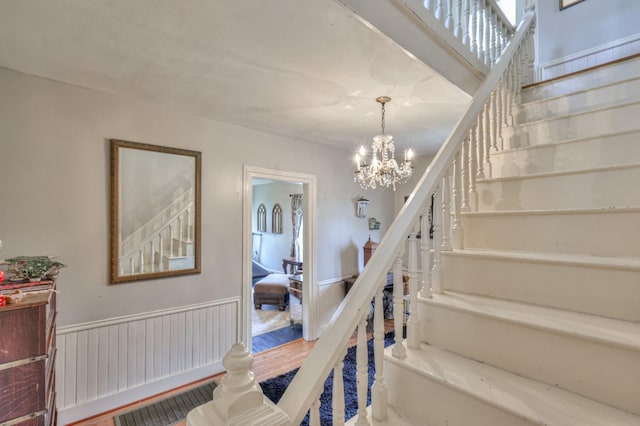 staircase featuring wainscoting and an inviting chandelier