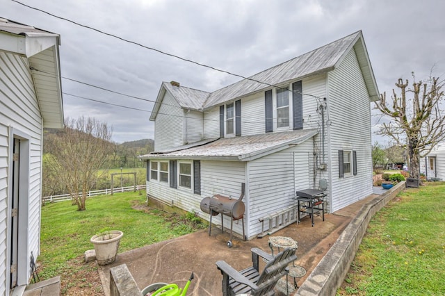 view of side of property with metal roof, a yard, and fence