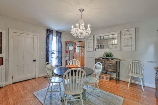 dining area featuring a chandelier, light wood finished floors, and baseboards