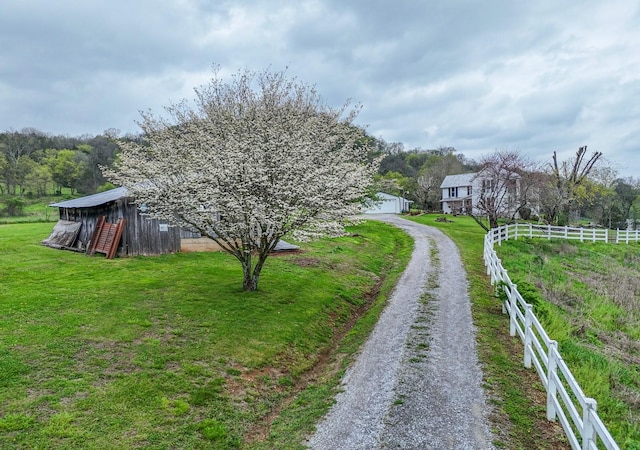 view of yard with gravel driveway, a garage, fence, and an outdoor structure