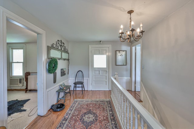 hallway with cooling unit, a chandelier, and wood finished floors