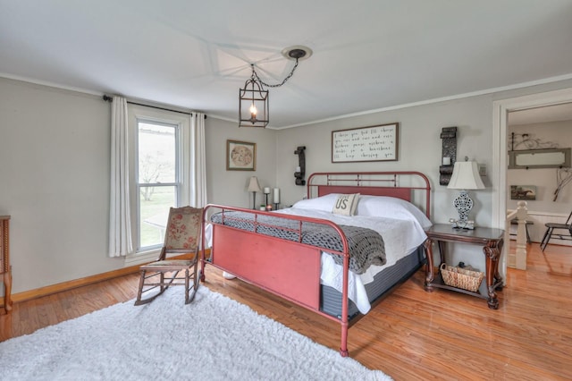 bedroom with baseboards, ornamental molding, and wood finished floors