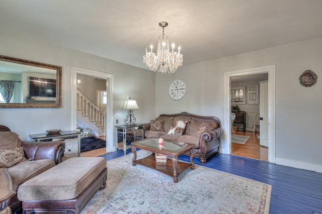 living area featuring an inviting chandelier, stairway, baseboards, and wood finished floors