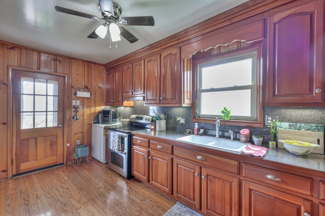 kitchen featuring range with two ovens, tasteful backsplash, light wood-style floors, a sink, and ceiling fan