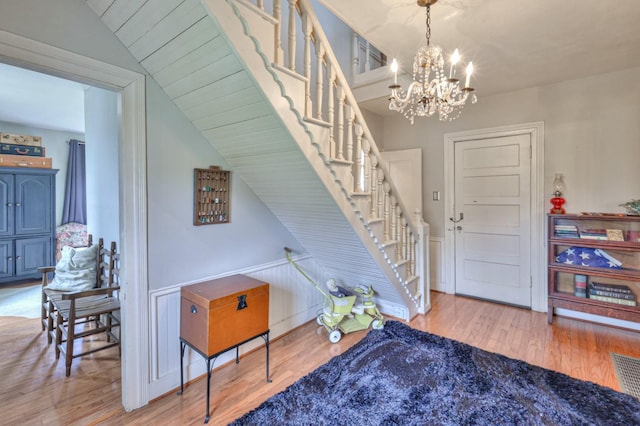 stairs with wood finished floors and an inviting chandelier