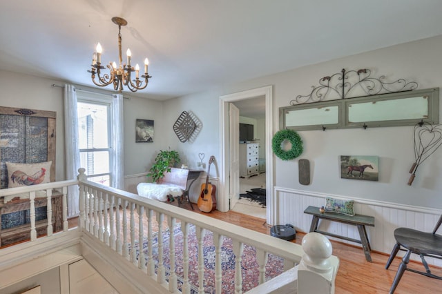 interior space with a wainscoted wall, an inviting chandelier, and wood finished floors