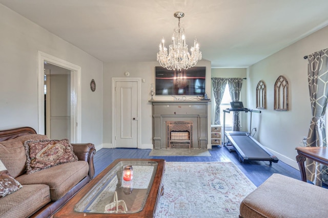 living room featuring a notable chandelier, wood finished floors, a fireplace with flush hearth, and baseboards