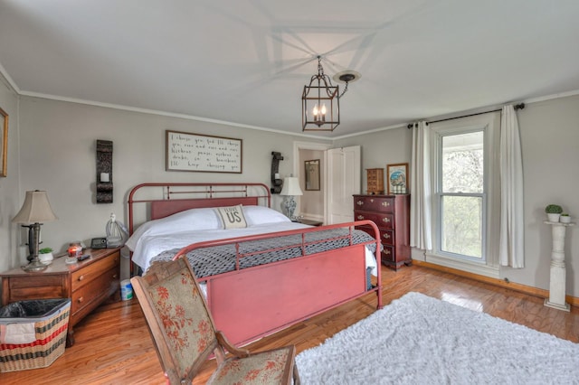 bedroom featuring baseboards, light wood-style flooring, a chandelier, and crown molding