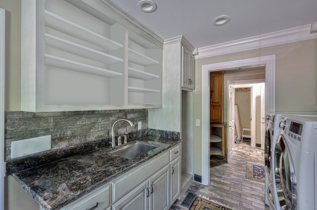 kitchen featuring washer and dryer, sink, dark stone countertops, and backsplash