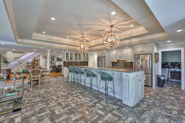 kitchen with stainless steel refrigerator, hanging light fixtures, and a raised ceiling