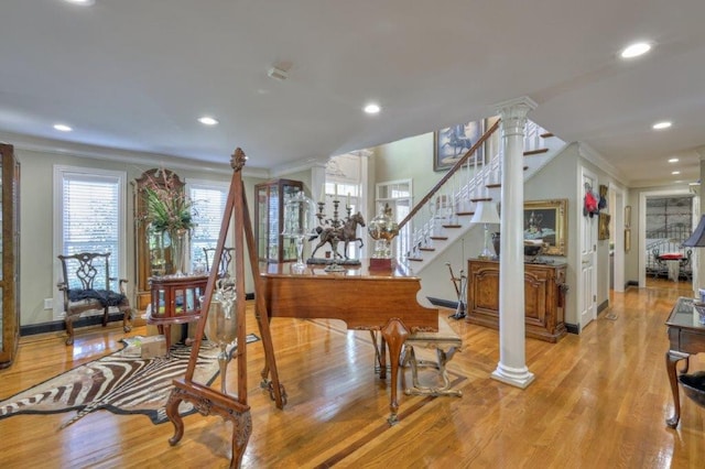 interior space with light wood-type flooring, decorative columns, and crown molding