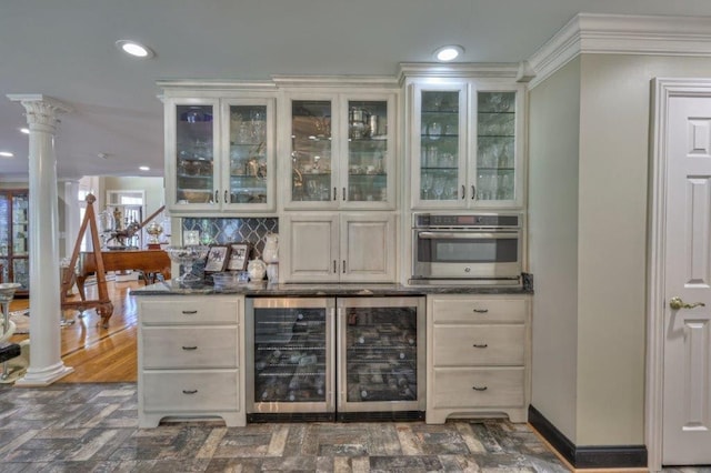 bar featuring decorative columns, dark hardwood / wood-style flooring, crown molding, wine cooler, and oven