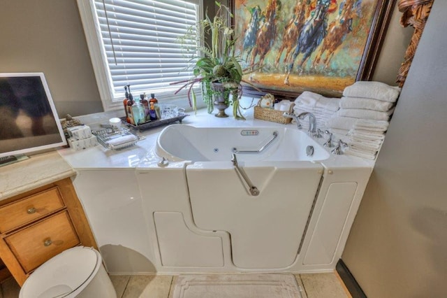 bathroom with toilet, a bathing tub, and tile patterned flooring