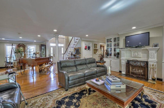 living room with light wood-type flooring, ornate columns, and ornamental molding