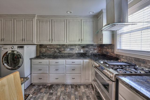 kitchen with backsplash, dark stone counters, dark wood-type flooring, range with two ovens, and wall chimney exhaust hood