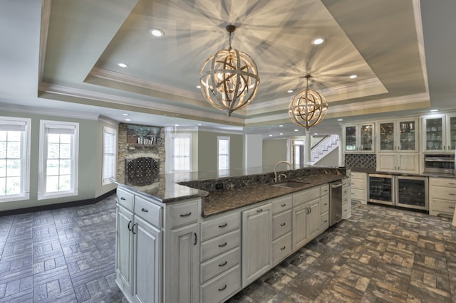 kitchen featuring a chandelier, a raised ceiling, stainless steel oven, hanging light fixtures, and a center island