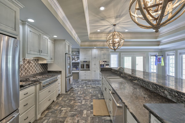 kitchen featuring decorative backsplash, a raised ceiling, hanging light fixtures, stainless steel appliances, and sink