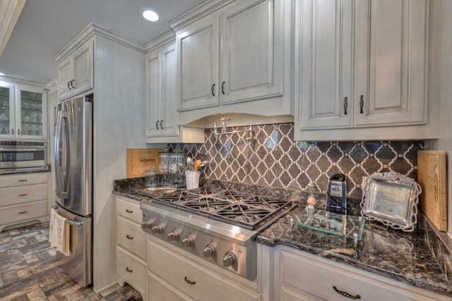 kitchen with dark stone countertops, backsplash, stainless steel appliances, and white cabinets