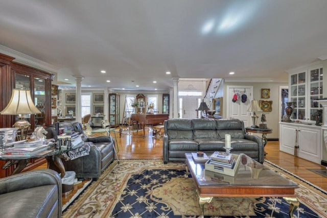 living room featuring decorative columns, light wood-type flooring, and crown molding