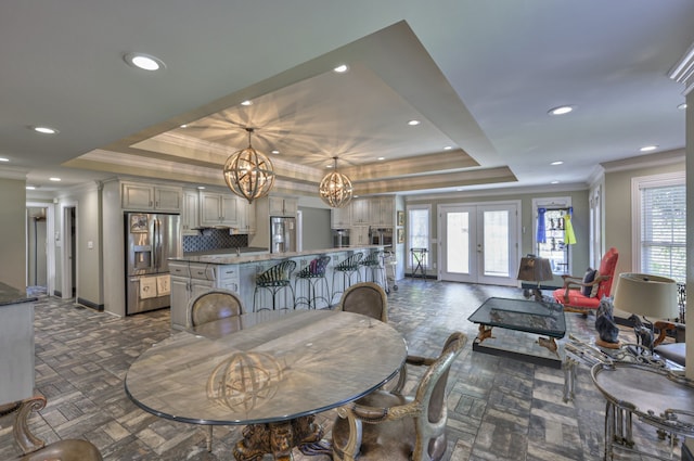 dining room featuring a raised ceiling, ornamental molding, and an inviting chandelier